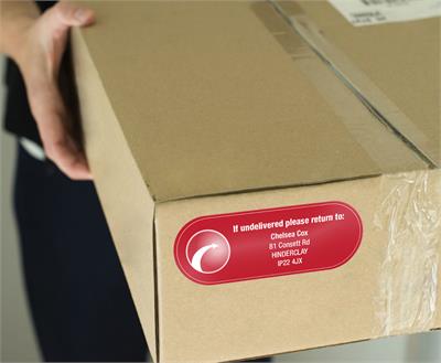 Address label on a cardboard parcel showing return details with a red design and white text for sender information.